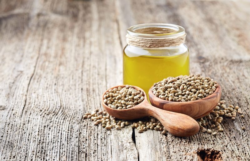 CBD seeds in a bowl next to a jar of hemp oil